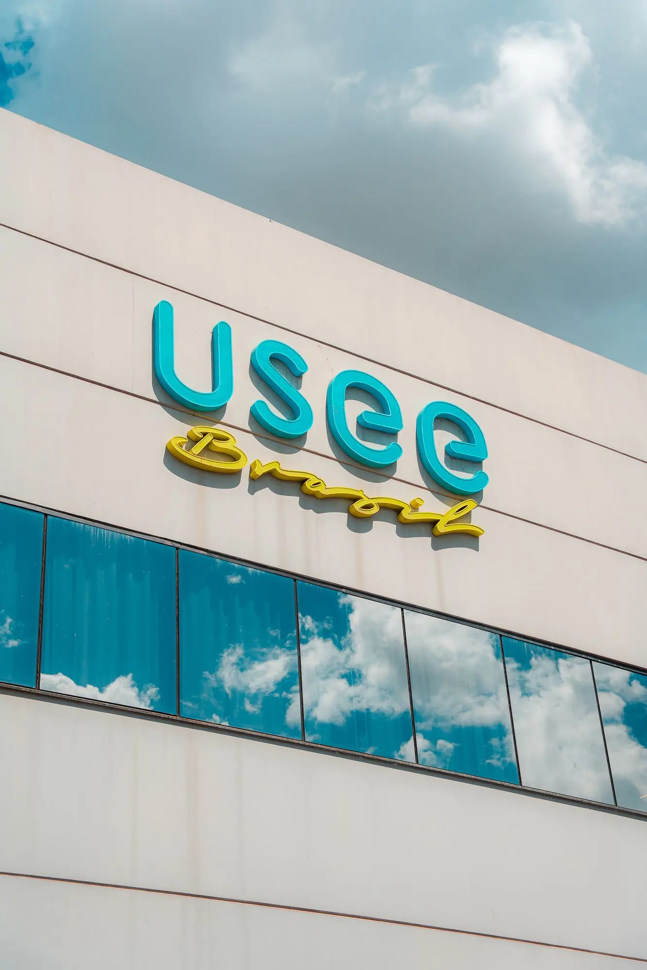 Fachada do prédio da Usee Brasil com o logotipo em azul sob céu aberto.