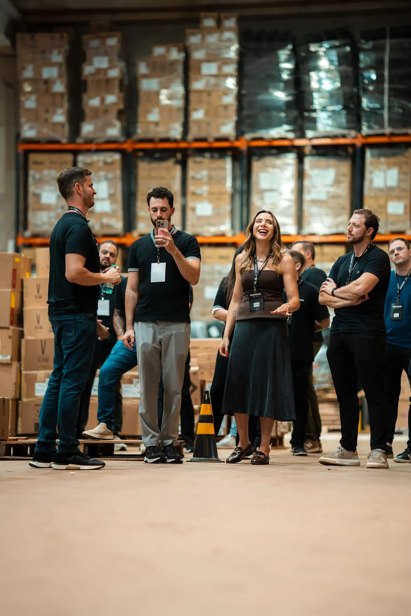 Empresários em visita guiada ao estoque da Usee Brasil, entre prateleiras e caixas, durante uma experiência anterior de bastidores.